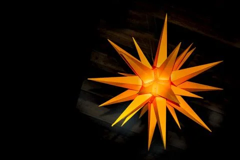 An orange decoration in the shape of multi-pointed star hanging from a ceilin Stock Photos