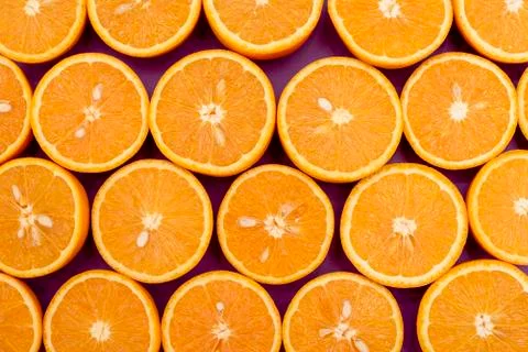Orange delicious oranges split in half lie in a row on purple Stock Photos