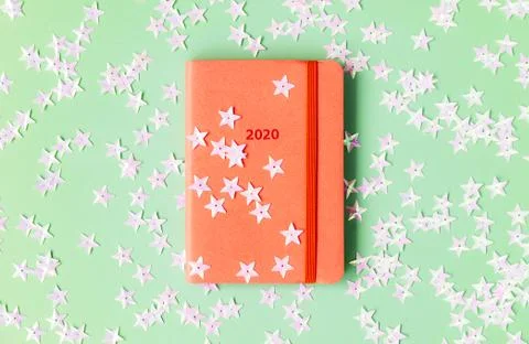 Orange diary for 2020 on a mint background strewn with light pink stars. Stock Photos