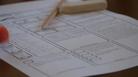 Orange die rolling onto D&amp;D character sheet Stock Footage 100310037