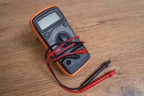 Orange digital multimeter with test probes on wooden background for electri.. Stock Photos