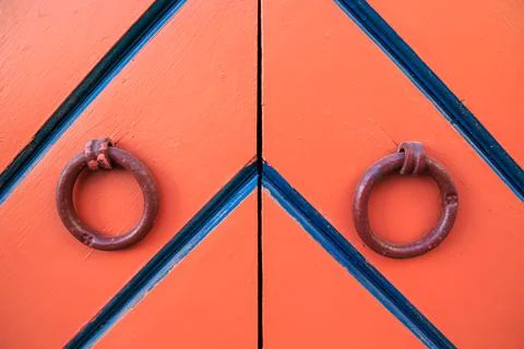 Orange double door and ring knockers. Diagonal black and blue stripes in Stock Photos