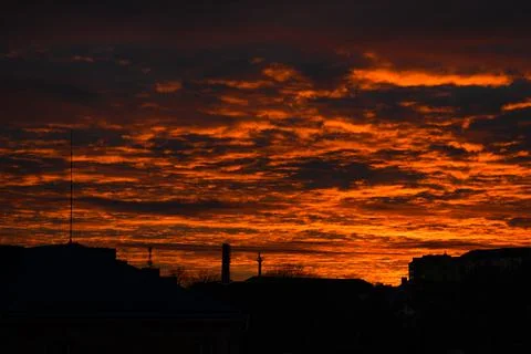 Orange dramatic city sunset. Dawn fire in the sky over a small city. Scenic l Stock Photos