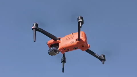 Orange drone flying in clear blue sky, showcasing aerial capabilities and design Vídeos de archivo 346086504