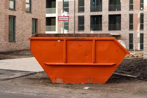 Orange dumpster on construction site near new buildings Stock Photos
