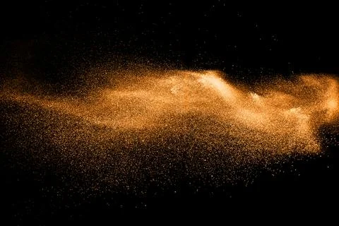 Orange dust particles explosion on black background. Color powder dust splash Stock Photos