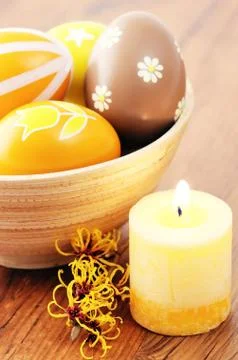 Orange easter eggs in a cup with american witchhazel twig and candle Stock Photos