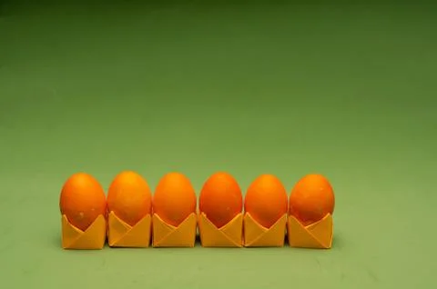 Orange easter eggs on origami stands in a row. Easter concept Stock Photos