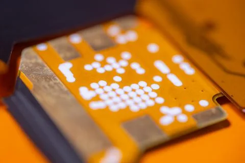 Orange electronic circuit board with white solder points and metallic conta.. Stock Photos