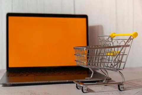 Orange empty screen of computer laptop with shopping cart. E-commerce Online Stock Photos