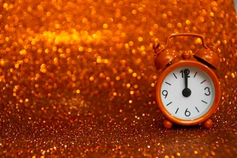 Orange evening clock on the right side of the photo ticks at noon or midnight Foto stock