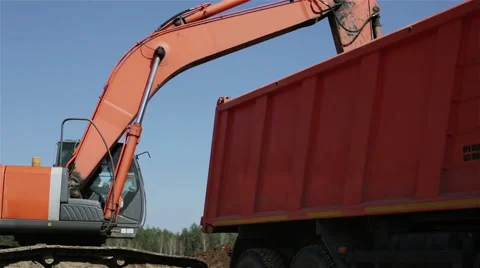 Orange excavator and orange dump truck on a background of blue sky Stock Footage 62703266