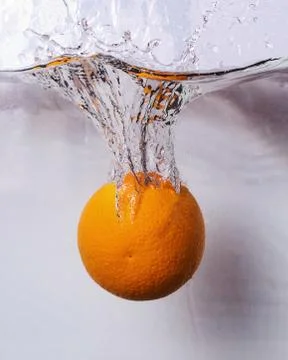 Orange falling into the water and creating splashes Stock Photos