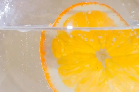 An orange falling into the water. Bright background Stock Photos