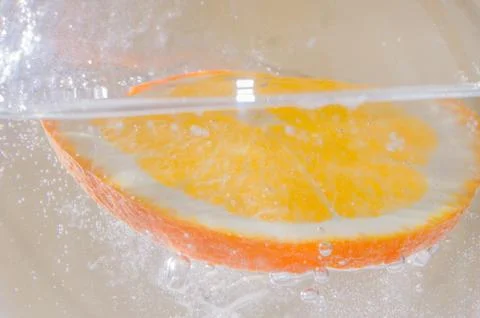 An orange falling into the water. Bright background Stock Photos