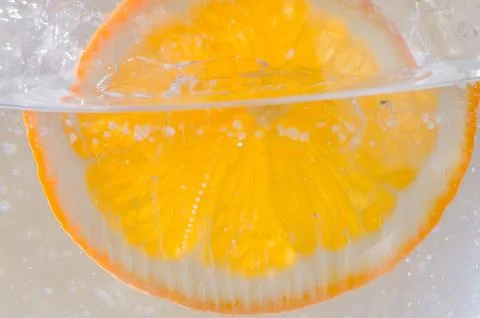 An orange falling into the water. Bright background Stock Photos