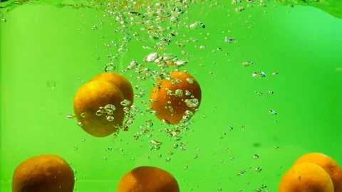 The orange falls into the water on the green background. Slow motion. 库存影片 145350194