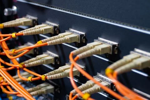 Orange fiber optic cables connected to network switch Stock Photos