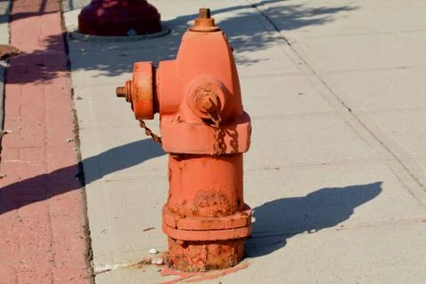 Orange fire hydrant in the bright midday sun Stock Photos