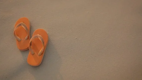 A orange flip flop on white sandy beach  in sunset. Summer vacation Stock Footage 86202945