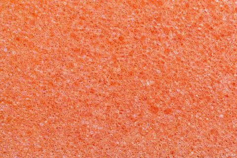 Orange foam kitchen sponge texture. Macro photography of porous material surface Stock Photos