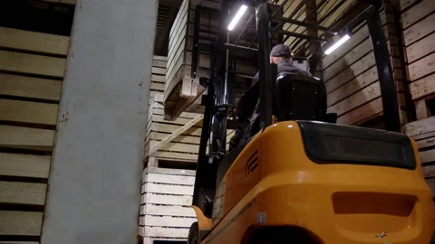 Orange forklift with unrecognizable driver stack wooden boxes on top of each Stock Footage 228129719
