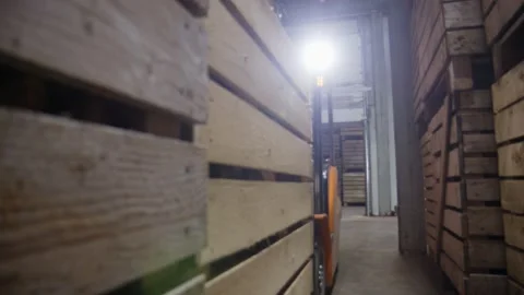Orange forklift with unrecognizable driver stack wooden boxes on top of each Stock Footage 228887366