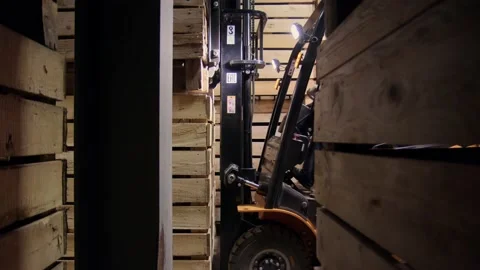 Orange forklift with unrecognizable driver stack wooden boxes on top of each Stock Footage 229341422
