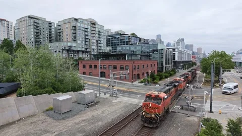 Orange freight train moving through urban rail yard in Seattle Stock Footage 339116214