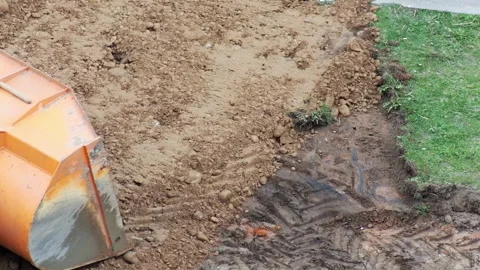 Orange front end loader bucket scooping dirt from ground, moving earth for Stock Footage 347580497