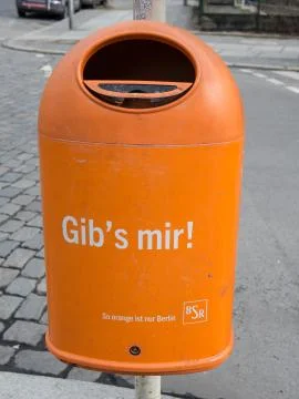 Orange Garbage Can With Text Give It To Me In German Language Stock Photos