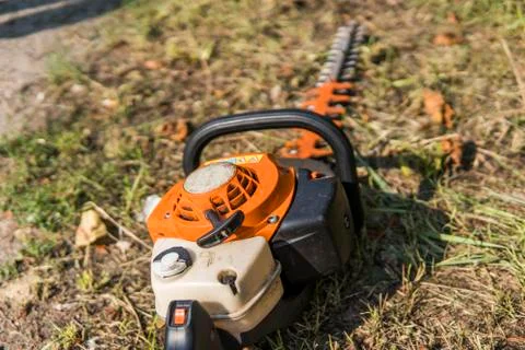 Orange gasoline engine portable chainsaw on a grass. Stock Photos