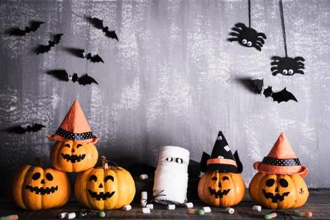 Orange ghost pumpkins with witch hat on gray wooden board background with bat Stock Photos