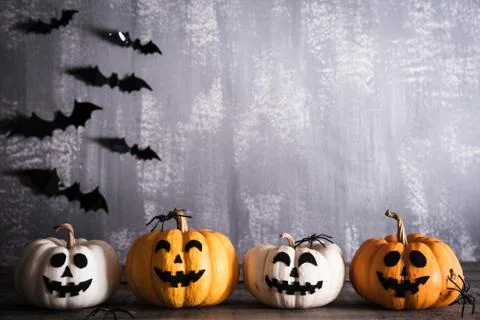 Orange ghost pumpkins with witch hat on gray wooden board background with bat Stock Photos