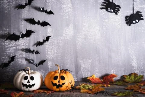 Orange ghost pumpkins with witch hat on gray wooden board background with bat Stock Photos