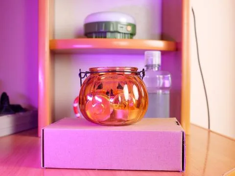 Orange glass lantern standing on cardboard box in cozy home interior with she Stock Photos