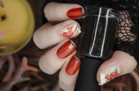 Orange glitter nails with black tips on a cozy hygge style background. Stock Photos