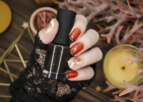 Orange glitter nails with black tips on a cozy hygge style background. Stock Photos