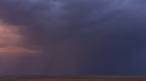 Orange glow in sky with lightning flashing near rainstorm on horizon Stock Footage 59526302