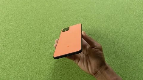 Orange google pixel 4 xl phone on green background Stock Footage 321751678