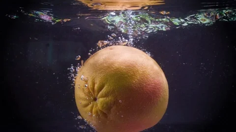 Orange grapefruit falling down into water with splashes. Stock Footage 122979610