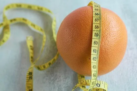 Orange grapefruit. Measuring tape in centimeters. Measuring tape around grape Stock Photos