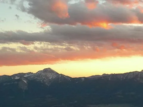 Orange-gray clouds over large rocky mountains Foto stock