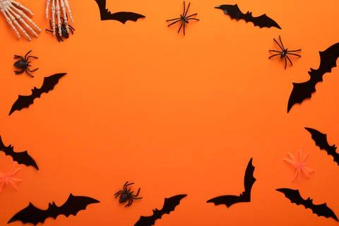 Orange Halloween background. Flock of black bats, spider, pumpkin, skeleton a Stock Photos