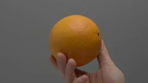 Orange in hand on a gray background. Stockbeeldmateriaal 265758753