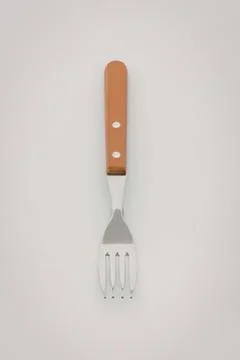 Orange handled metal fork on plain background Stock Photos