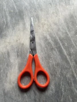 Orange-Handled Scissors on a Concrete Surface Stock Photos