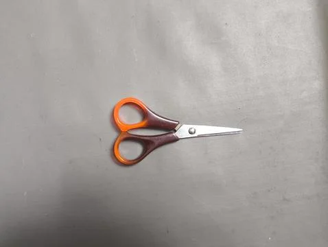 Orange-handled scissors float against pure black background Stock-Fotos