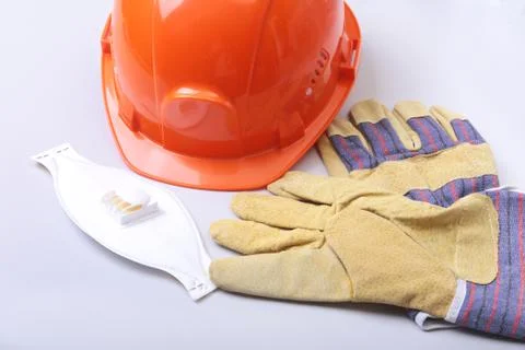 Orange hard hat, goggles, protective mask, respirator and safety gloves on a Stock Photos