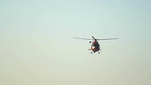 An orange helicopter flies along the coast over the ocean, slow motion. Stock Footage 71377576